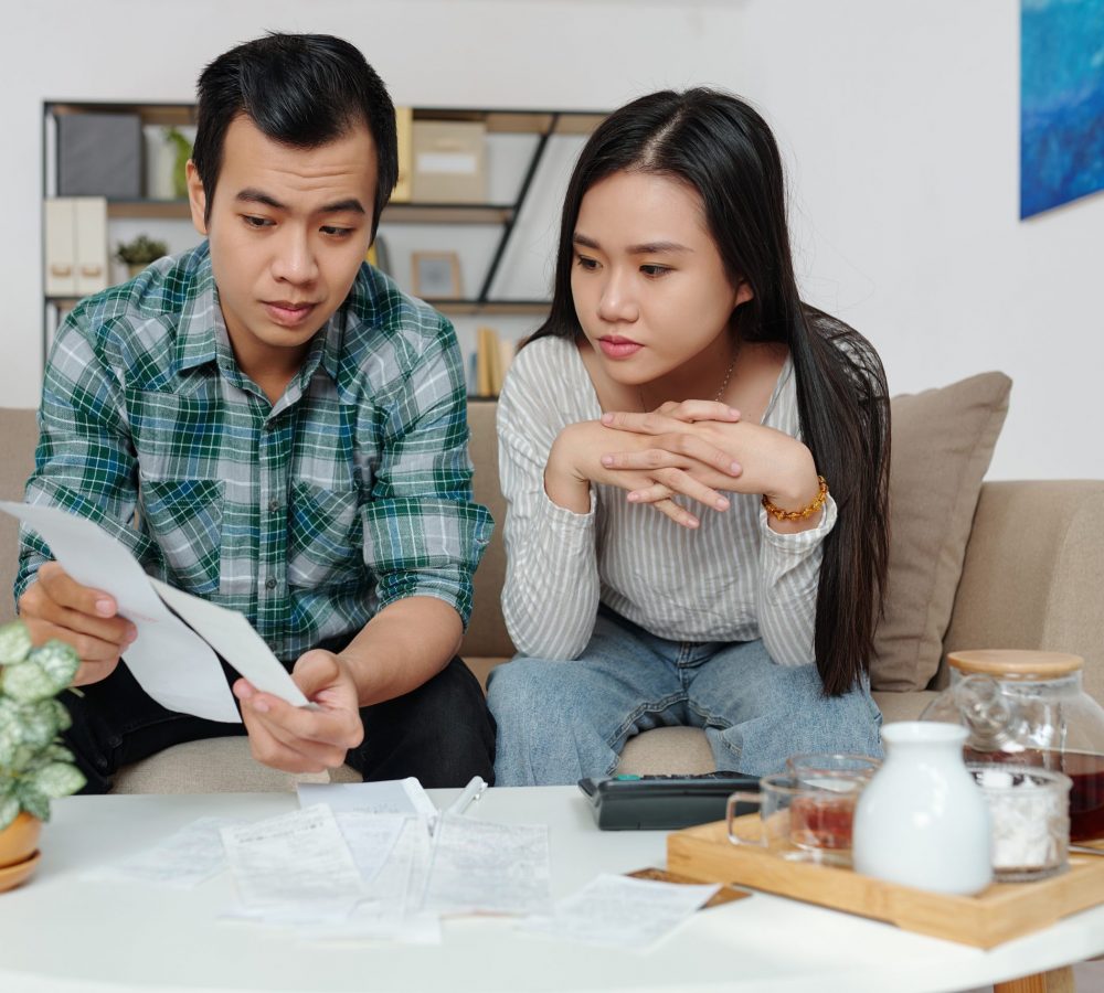 Vietnamese young man showing bills to girlfriend when they are discussing and managing personal expenses and utility bills